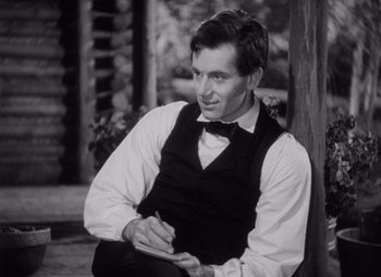 Movie still from “Young Mr. Lincoln” (1939), directed by John Ford – A black and white photo of a man in a vest and tie writing; Medium shot, High angle