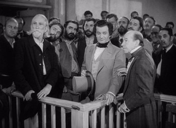 Movie still from “Young Mr. Lincoln” (1939), directed by John Ford – A group of men standing next to each other in front of a railing; Medium shot, Over the shoulder angle