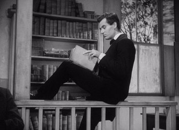 Movie still from “Young Mr. Lincoln” (1939), directed by John Ford – A man sitting on a bench with a book in his hands; Medium shot, Low angle