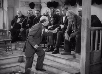 Movie still from “Young Mr. Lincoln” (1939), directed by John Ford – An older man in a suit and tie standing in front of a group of people; Wide shot, Over the shoulder angle