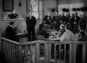 Movie still from “Young Mr. Lincoln” (1939), directed by John Ford – A man in a courtroom is standing in front of a group of people; Wide shot, High angle