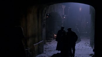 Movie still from “Young Sherlock Holmes” (1985), directed by Barry Levinson – Two people in a dark alley with a fire in the background; Wide shot, High angle