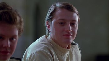 Movie still from “Young Sherlock Holmes” (1985), directed by Barry Levinson – A young man wearing a white shirt is looking at the camera; Close Up shot, Low angle