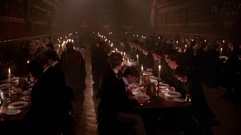 Movie still from “Young Sherlock Holmes” (1985), directed by Barry Levinson – A group of people sitting at a table with candles; Wide shot, High angle