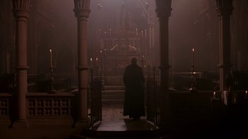 Movie still from “Young Sherlock Holmes” (1985), directed by Barry Levinson – A man standing in front of an altar in a church; Wide shot, Low angle