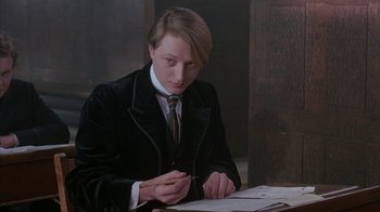 Movie still from “Young Sherlock Holmes” (1985), directed by Barry Levinson – A man in a suit and tie writing on a piece of paper; Medium shot, Low angle