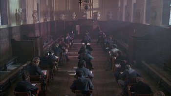 Movie still from “Young Sherlock Holmes” (1985), directed by Barry Levinson – A group of people sitting at tables in a room; Wide shot, High angle