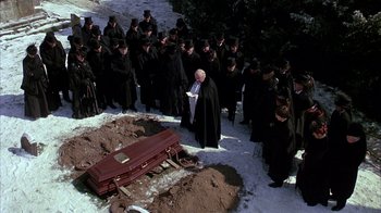 Movie still from “Young Sherlock Holmes” (1985), directed by Barry Levinson – A group of people standing in front of an open casket in the snow; Wide shot, High angle