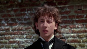 Movie still from “Young Sherlock Holmes” (1985), directed by Barry Levinson – A young man wearing a black suit and a black tie; Close Up shot, Low angle