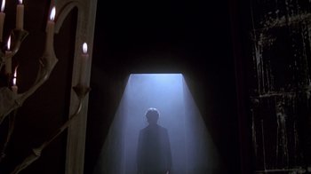 Movie still from “Young Sherlock Holmes” (1985), directed by Barry Levinson – A man standing in a dark room with a light shining on him; Wide shot, Low angle
