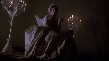Movie still from “Young Sherlock Holmes” (1985), directed by Barry Levinson – A woman sitting in front of a bunch of lit candles; Wide shot, High angle