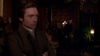 Movie still from “Young Sherlock Holmes” (1985), directed by Barry Levinson – A man standing in front of another man in a room; Medium shot, Over the shoulder angle