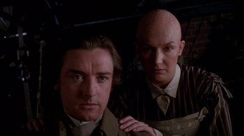 Movie still from “Young Sherlock Holmes” (1985), directed by Barry Levinson – A man and a bald man standing next to each other; Close Up shot, Low angle