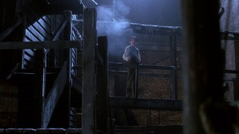 Movie still from “Young Sherlock Holmes” (1985), directed by Barry Levinson – A man standing on top of a wooden railing; Wide shot, Low angle
