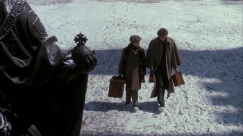 Movie still from “Young Sherlock Holmes” (1985), directed by Barry Levinson – Two people walking in the snow with their luggage; Wide shot, High angle