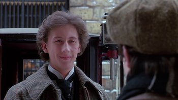 Movie still from “Young Sherlock Holmes” (1985), directed by Barry Levinson – A young man wearing a coat and a hat; Close Up shot, Over the shoulder angle