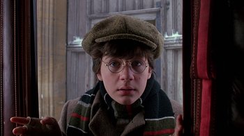 Movie still from “Young Sherlock Holmes” (1985), directed by Barry Levinson – A young boy wearing a hat and glasses; Close Up shot, Over the shoulder angle