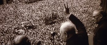 Movie still from “Young Winston” (1972), directed by Richard Attenborough – An old photo of a man giving a speech to a crowd; Medium shot, High angle