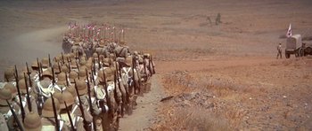 Movie still from “Young Winston” (1972), directed by Richard Attenborough – Many soldiers marching down a dirt road; Extreme Wide shot, High angle