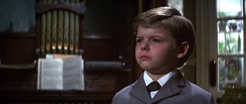 Movie still from “Young Winston” (1972), directed by Richard Attenborough – A young boy in a suit and tie looking sad; Close Up shot, Low angle
