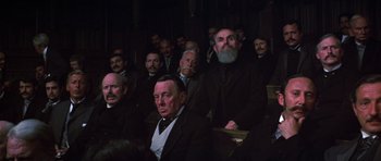 Movie still from “Young Winston” (1972), directed by Richard Attenborough – A group of men sitting in a dark room; Medium shot, High angle