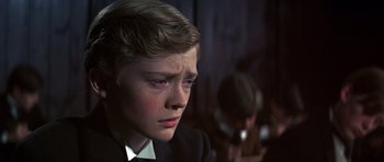 Movie still from “Young Winston” (1972), directed by Richard Attenborough – A young boy in a suit and tie looking sad; Close Up shot, Over the shoulder angle