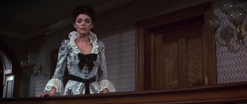 Movie still from “Young Winston” (1972), directed by Richard Attenborough – A woman standing in front of a door wearing a white dress; Medium shot, Over the shoulder angle