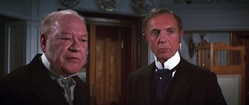 Movie still from “Young Winston” (1972), directed by Richard Attenborough – Two men in suits standing next to each other in a room; Close Up shot, Over the shoulder angle