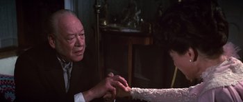 Movie still from “Young Winston” (1972), directed by Richard Attenborough – An older man holding a woman's hand while sitting in a chair; Close Up shot, High angle