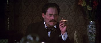 Movie still from “Young Winston” (1972), directed by Richard Attenborough – A man in a suit and bow tie holding a cigarette in his mouth; Close Up shot, Low angle