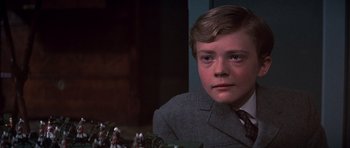Movie still from “Young Winston” (1972), directed by Richard Attenborough – A young boy in a suit and tie looking into the camera; Close Up shot, Over the shoulder angle