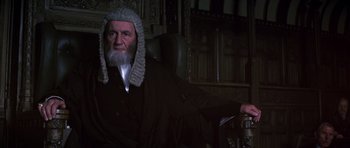 Movie still from “Young Winston” (1972), directed by Richard Attenborough – An old man wearing a wig and a judge's wig; Medium shot, Low angle