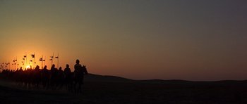 Movie still from “Young Winston” (1972), directed by Richard Attenborough – A person riding a horse in a field at sunset; Extreme Wide shot, Low angle