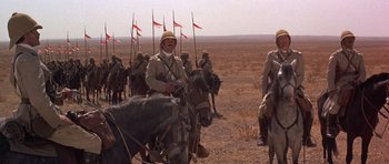 Movie still from “Young Winston” (1972), directed by Richard Attenborough – A group of men riding horses on a dirt field; Wide shot, Low angle