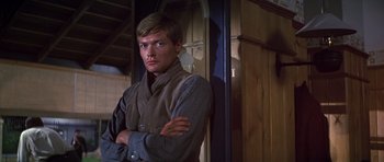 Movie still from “Young Winston” (1972), directed by Richard Attenborough – A man standing with his arms crossed in front of a door; Close Up shot, Low angle