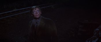 Movie still from “Young Winston” (1972), directed by Richard Attenborough – A man standing in the dark wearing a scarf; Medium shot, Low angle