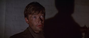 Movie still from “Young Winston” (1972), directed by Richard Attenborough – A young man with brown hair wearing a brown sweater; Close Up shot, Low angle