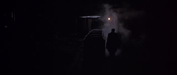 Movie still from “Young Winston” (1972), directed by Richard Attenborough – A man is standing in the dark near a train; Wide shot, High angle