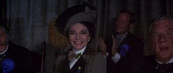 Movie still from “Young Winston” (1972), directed by Richard Attenborough – A woman wearing a hat and a bow tie; Close Up shot, Over the shoulder angle