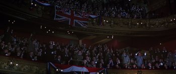 Movie still from “Young Winston” (1972), directed by Richard Attenborough – A crowd of people in a theater with british flags; Extreme Wide shot, High angle