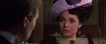 Movie still from “Young Winston” (1972), directed by Richard Attenborough – An older woman wearing a purple hat looking at a young man; Close Up shot, Over the shoulder angle