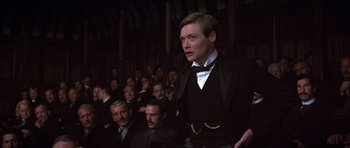 Movie still from “Young Winston” (1972), directed by Richard Attenborough – A man standing in front of a group of people; Medium shot, Low angle