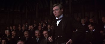 Movie still from “Young Winston” (1972), directed by Richard Attenborough – A man standing in front of a group of people; Medium shot, Low angle