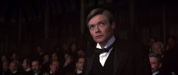 Movie still from “Young Winston” (1972), directed by Richard Attenborough – A man wearing a suit and bow tie in front of an audience; Close Up shot, Low angle