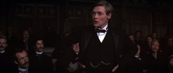 Movie still from “Young Winston” (1972), directed by Richard Attenborough – A man in a suit and bow tie talking; Close Up shot, Low angle
