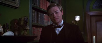 Movie still from “Young Winston” (1972), directed by Richard Attenborough – A man in a suit and bow tie in front of a book shelf; Close Up shot, Low angle