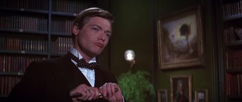 Movie still from “Young Winston” (1972), directed by Richard Attenborough – A man in a suit and bow tie holding a pair of scissors; Close Up shot, Low angle