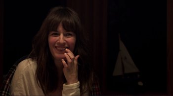 Movie still from “Your Sister's Sister” (2011), directed by Lynn Shelton – A woman smiles while holding her hand to her mouth; Close Up shot, Over the shoulder angle