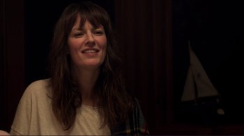 Movie still from “Your Sister's Sister” (2011), directed by Lynn Shelton – A woman with long brown hair smiles for the camera; Close Up shot, Over the shoulder angle