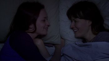 Movie still from “Your Sister's Sister” (2011), directed by Lynn Shelton – Two women are laying in a bed and smiling at each other; Close Up shot, Overhead angle